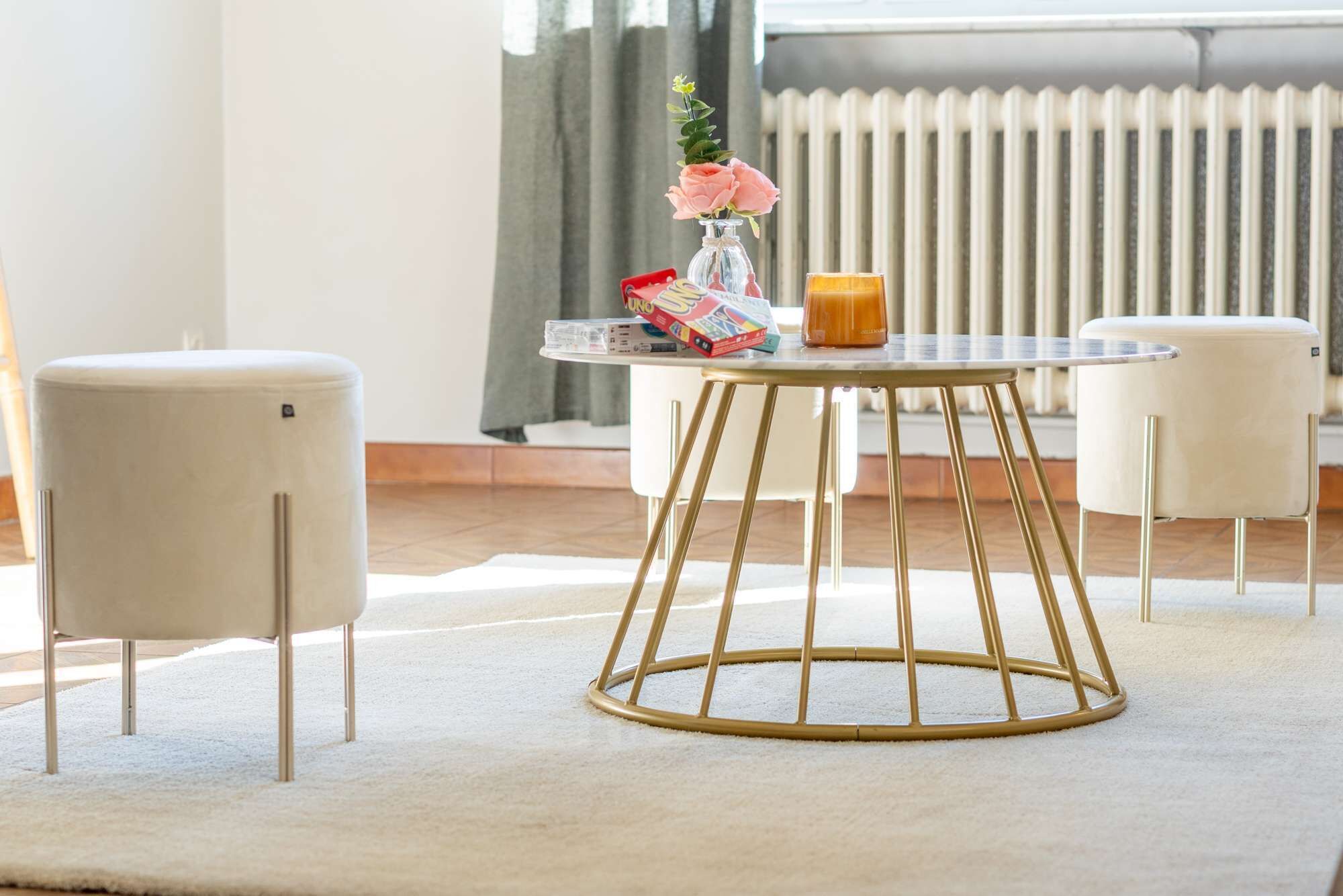 Een moderne kamer met een ronde tafel, twee witte stoelen, een bloemenvaas, een tijdschrift en een kaars.