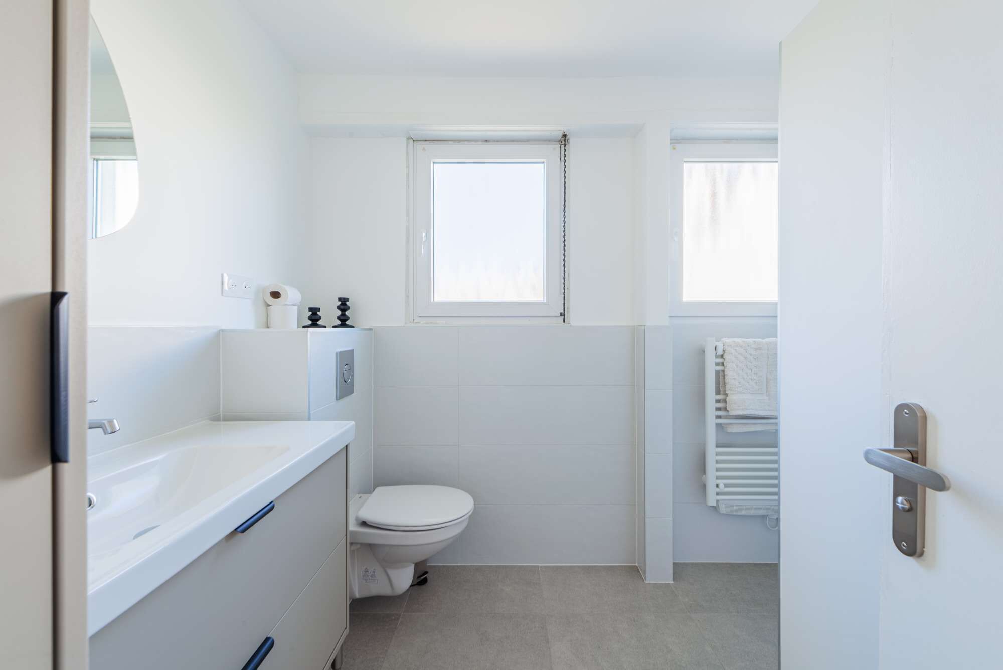 A compact bathroom with a toilet, a sink, and a window.
