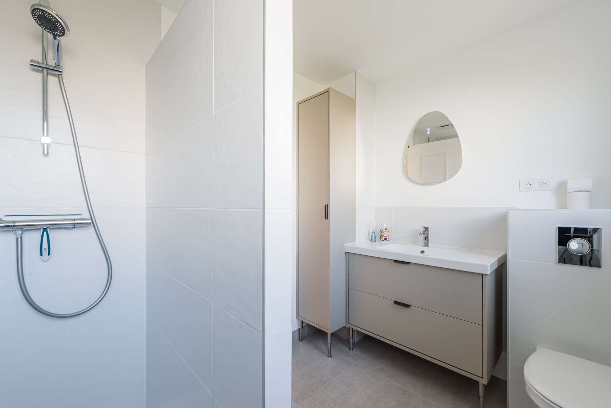 Ein Badezimmer mit Dusche, Waschbecken, Spiegel und Toilette.