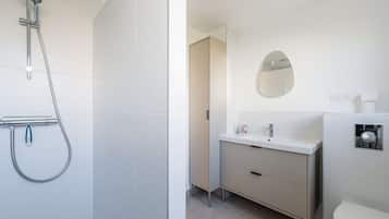 Ein Badezimmer mit Dusche, Waschbecken, Spiegel und Toilette.