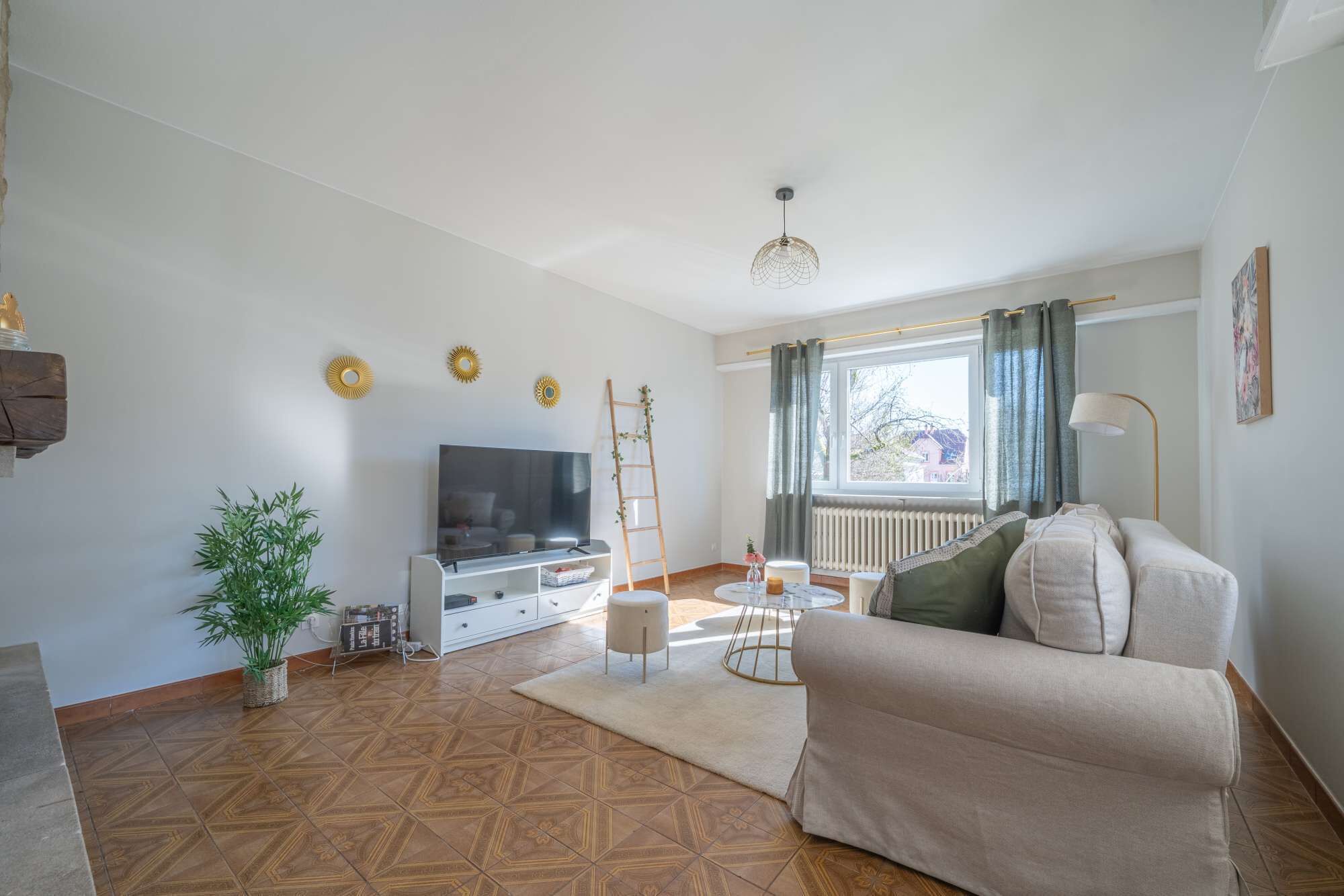 En stue med fjernsyn, sofa og en plante.