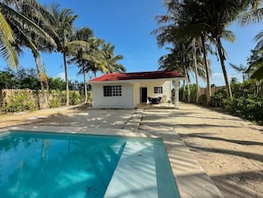 Ein Haus mit Swimmingpool, umgeben von Palmen und blauem Himmel.