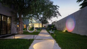 Un chemin menant à un bâtiment à la façade en verre, entouré de pelouse et d’arbres.
