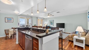 A spacious kitchen with a central island, pendant lighting, and a ceiling fan.