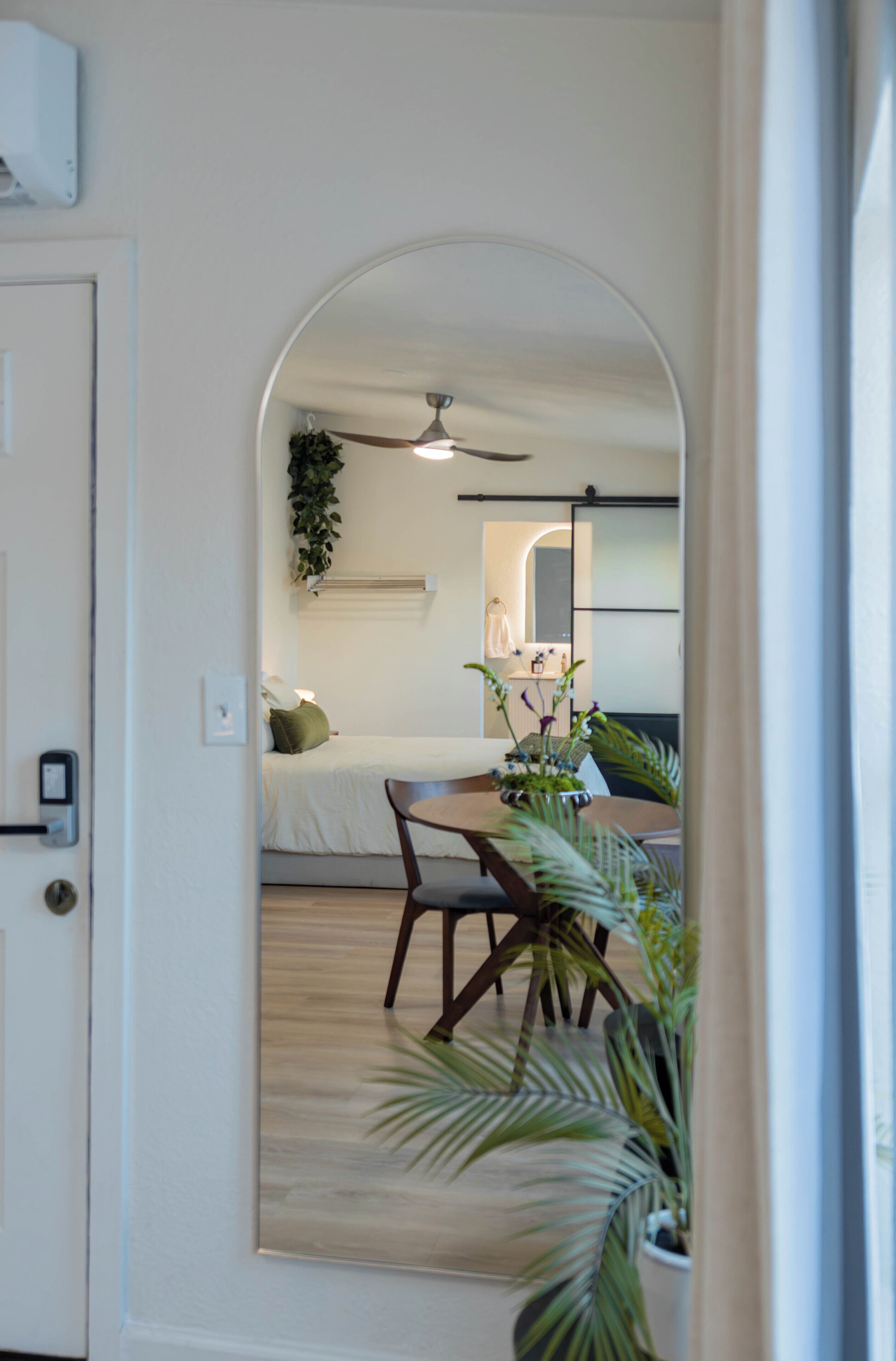 An arched doorway leading to a bedroom with a bed, a ceiling fan, and a bedside table with a lamp.. Modern Private Guesthouse with Patio near Universal+Downtown+Airport in Orlando