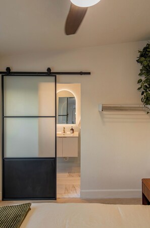 Et moderne badeværelse med skydedør, spejl, vask og radiator.