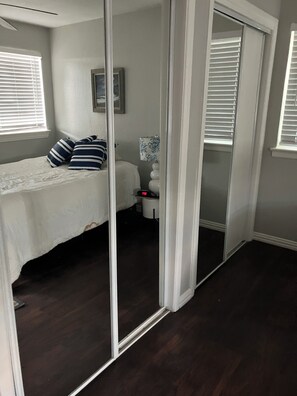 Ein Schlafzimmer mit Bett, Nachttisch, Lampe und Spiegel.