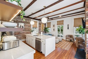 A modern kitchen with a built-in island, white cabinetry, and a brick wall. - The Plunge at King Street w/ Private Pool (Charleston)