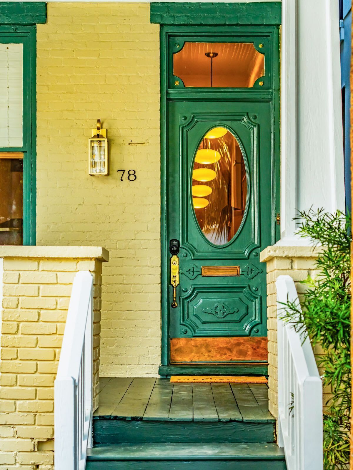 A green door with a number '78' above it, a lantern on the wall, and a small step leading up to the door.