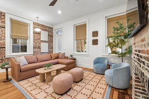 Ein Wohnzimmer mit Ecksofa, Poufs, Couchtisch und blauem Sessel.