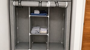 Un dressing ouvert avec trois étagères et une tringle à vêtements, doté d’un revêtement en tissu gris.