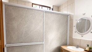 Une salle de bain avec une douche, un lavabo, un miroir et un tapis à motifs.