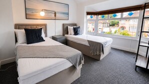 Habitación de hotel con dos camas, ventana con vistas, un cuadro en la pared y una lámpara.