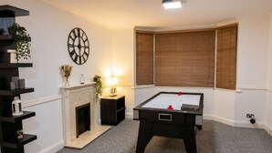 Una habitación con mesa de futbolín, chimenea y un reloj de pared.