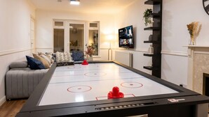 Una habitación con mesa de juego de discos, sofá, televisor y chimenea.