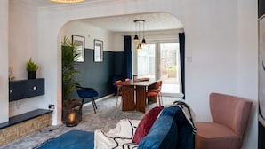 A modern living room with a dining area, a sofa, a chair, and a hanging light fixture. - 4-Bed Headington Home · Sleeps 8 with Parking · Walk to JR Hospital (Headington)