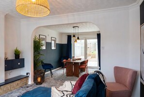Ein modernes Wohnzimmer mit Essbereich, einer Couch, einem Sessel und einer Pendelleuchte.