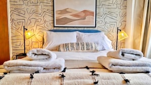 A neatly made bed with white linens, a framed artwork above it, and two bedside lamps. - 4-Bed Headington Home · Sleeps 8 with Parking · Walk to JR Hospital (Headington)