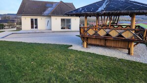 A house with a tiled roof, a glass door, and a thatched-roof structure. - Holiday Home 'Gîte Rural Le Vendangeoir' with Private Garden and Wi-Fi (Colombé-la-Fosse)