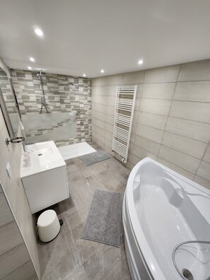 Et moderne badeværelse med badekar, brusebad, vask og toilet.