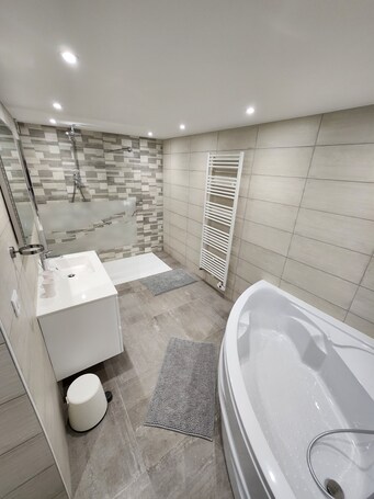 A modern bathroom with a bathtub, a shower, a sink, and a toilet.. Holiday Home 'Gîte Rural Le Vendangeoir' with Private Garden and Wi-Fi