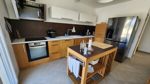 A modern kitchen with a built-in oven, microwave, and stainless steel refrigerator. - Holiday Home 'Gîte Rural Le Vendangeoir' with Private Garden and Wi-Fi (Colombé-la-Fosse)
