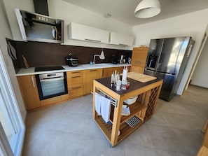 A modern kitchen with a built-in oven, microwave, and stainless steel refrigerator.