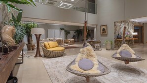 Un hall d’entrée spacieux avec un plafond haut, un mobilier moderne et des fauteuils suspendus.