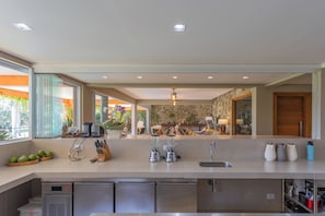 A modern kitchen with a large island, built-in appliances, and a view of the living area.