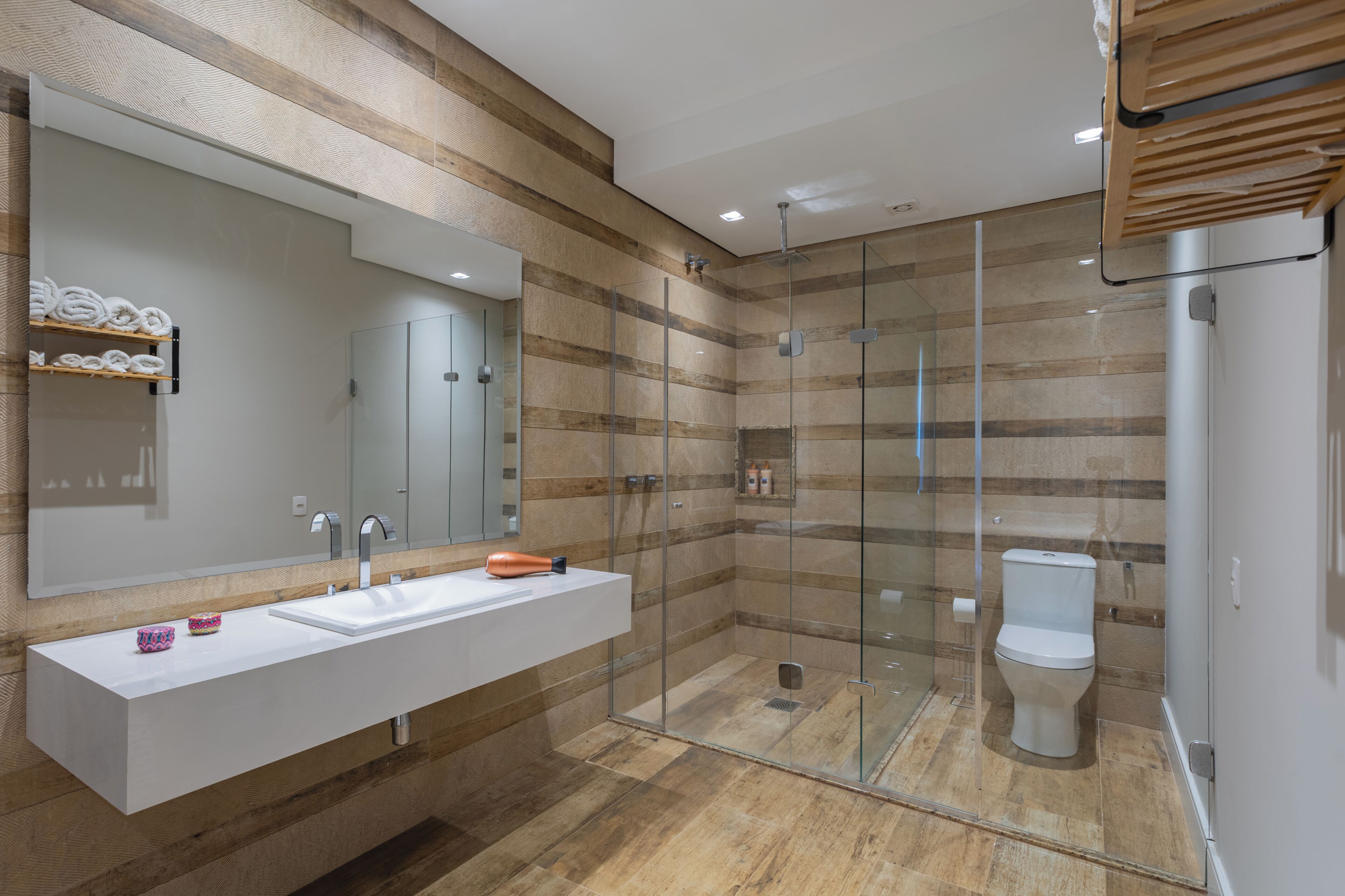 A modern bathroom with a glass-enclosed shower, a large mirror, and a white sink.