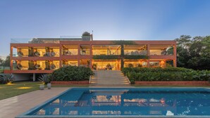 Un immeuble moderne à plusieurs étages, avec une piscine située devant.