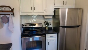 Uma cozinha com armários brancos, um fogão de aço inoxidável e uma geladeira.