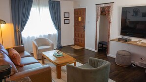 Uma sala de estar com sofá, poltrona, mesa de centro e televisão.