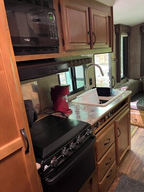 A compact kitchen with a microwave, stove, and sink.