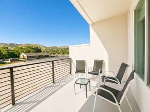 Ein Balkon mit Metallgeländer, einem kleinen Tisch und zwei Stühlen.