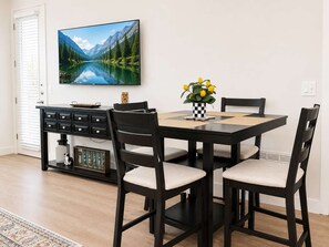 Ein Essbereich mit Tisch, Stühlen, einem Fernseher und einer Zierpflanze.