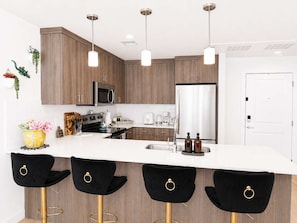 A modern kitchen with wooden cabinets, stainless steel appliances, and black bar stools. - Walk to Temple Square | Stylish SLC Getaway (Salt Lake City)