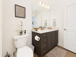 Une salle de bain moderne équipée de toilettes, d’un lavabo, d’un meuble-lavabo et d’un grand miroir.