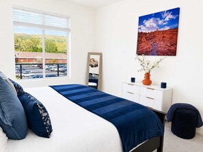 A bedroom with a bed, a dresser, a mirror, and a painting. - Walk to Temple Square | Stylish SLC Getaway (Salt Lake City)