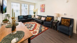Ein Wohnzimmer mit einer Couch, Sesseln, einem Couchtisch und einem gemusterten Teppich.