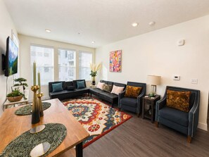 Ein Wohnzimmer mit einer Couch, Sesseln, einem Couchtisch und einem gemusterten Teppich.