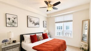Ein Schlafzimmer mit Bett, Nachttischen, Kommode, Deckenventilator und Bildern an der Wand.