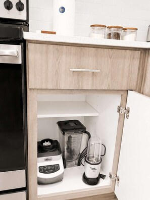 Eine Küche mit Einbauofen, Mixer und Kaffeemaschine auf der Arbeitsplatte.