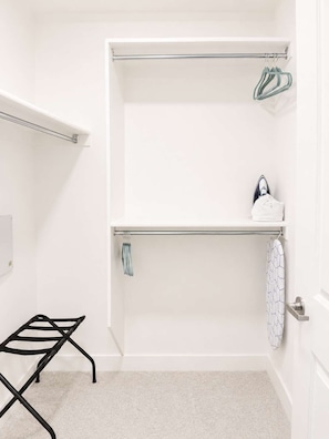 Ein Badezimmer mit einer weißen Dusche, einem Handtuchhalter, einem Wäscheständer und einem Handtuch an der Wand.