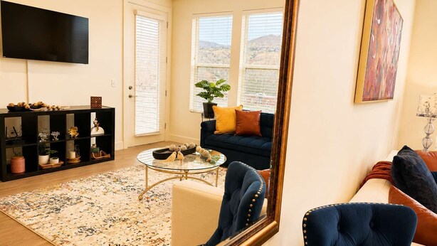 A living room with a TV, a sofa, a coffee table, and a bookshelf. - 2BR Urban Oasis in Downtown SLC - Sleeps 6, Gym (Salt Lake City)