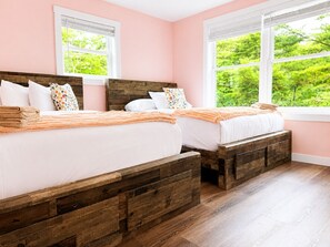 A bedroom with two wooden beds, white bedding, and a view of greenery through the windows. - The South Harmony House, Luxury Escape, HotTub, 5,000sqft, Gameroom (Lake Harmony)