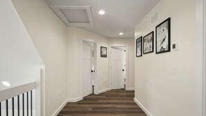 A hallway with wooden flooring, white walls, and a white railing on the left. - The South Harmony House, Luxury Escape, HotTub, 5,000sqft, Gameroom (Lake Harmony)