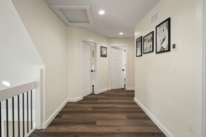 A hallway with wooden flooring, white walls, and a white railing on the left. - The South Harmony House, Luxury Escape, HotTub, 5,000sqft, Gameroom (Lake Harmony)