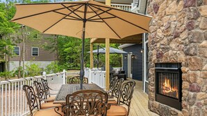 An outdoor patio with a table and chairs, a stone fireplace, and a view of a house. - The South Harmony House, Luxury Escape, HotTub, 5,000sqft, Gameroom (Lake Harmony)