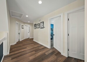 A hallway with wooden flooring, white walls, and closed doors leading to other rooms. - The South Harmony House, Luxury Escape, HotTub, 5,000sqft, Gameroom (Lake Harmony)